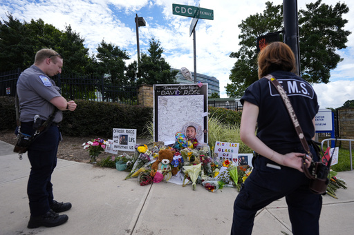 CORRECTS THAT OFFICER WAS KILLED, NOT WOUNDED - A memorial is seen in the aftermath of a shooting near the CDC where DeKalb County Police Officer David Rose was killed while responding, Wednesday, Aug. 13, 2025, in Atlanta. (AP Photo/Mike Stewart)