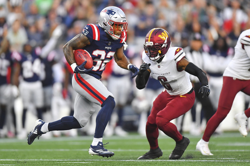 New England Patriots running back TreVeyon Henderson (32) runs the ball back for a touchdown against Washington Commanders cornerback Noah Igbinoghene (6) during the first half of an NFL preseason football game Friday, Aug. 8, 2025, in Foxborough, Mass. (AP Photo/Steven Senne)
