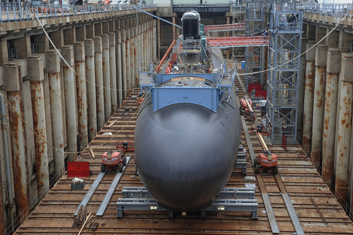 FILE- Shipyard workers at General Dynamics Electric Boat in Groton, Conn., prepare a submarine for float-off, July 30, 2015. (AP Photo/Jessica Hill, File)