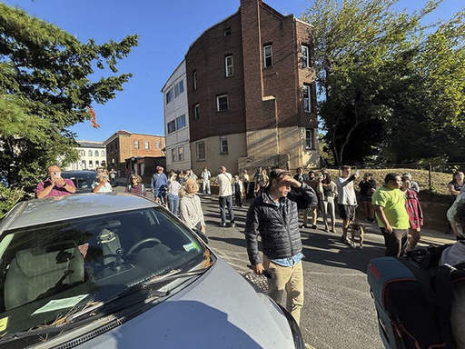 Residents from the Mount Pleasant neighborhood in Washington out in the street as Federal, and local law enforcement officer arrive to make arrest at a nearby apartment building, Wednesday, Aug. 27, 2025. (AP Photo/Collin Binkley)