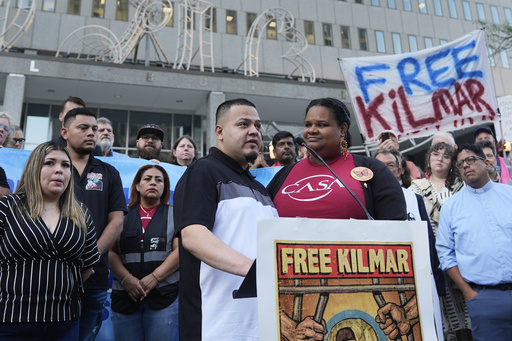 Jennifer Vasquez Sura, front left, and her husband Kilmar Abrego Garcia, front center, attend a protest rally at the Immigration and Customs Enforcement field office in Baltimore, Monday, Aug. 25, 2025, to support Kilmar Abrego Garcia. (AP Photo/Stephanie Scarbrough)
