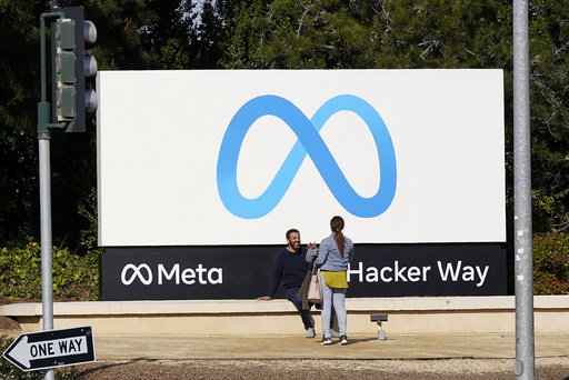 FILE - People talk near a Meta sign outside of the company's headquarters in Menlo Park, Calif., March 7, 2023. (AP Photo/Jeff Chiu, File)