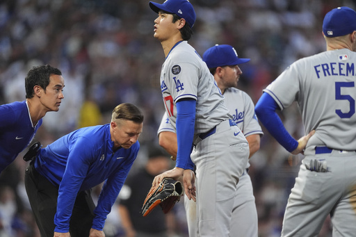 Los Angeles Dodgers starting pitcher Shohei Ohtani is checked on by a trainer after taking an RBI single off his thigh in the fourth inning of a baseball game against the Colorado Rockies Wednesday, Aug. 20, 2025, in Denver. (AP Photo/David Zalubowski)