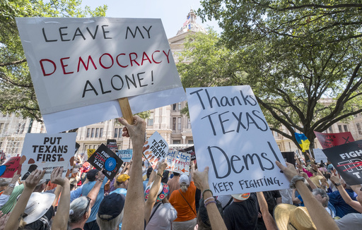 Protestors hold up signs during the Fight The Trump Takeover Rally held at the State Capitol, Saturday, Aug. 16, 2025, in Austin, Texas, to protest congressional redistricting efforts by Texas Republicans and President Donald Trump. (AP Photo/Rodolfo Gonzalez)
