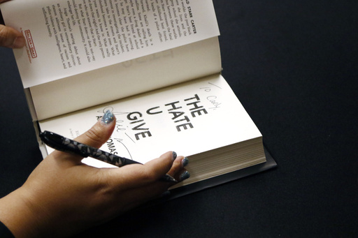 In this Oct. 10, 2018 photo, Angie Thomas, 30, a Jackson, Miss., resident whose book, "The Hate U Give," has been on a national young adult best-seller list for 82 weeks, finishes autographing a copy of her book at a reception in Jackson, Miss. (AP Photo/Rogelio V. Solis)