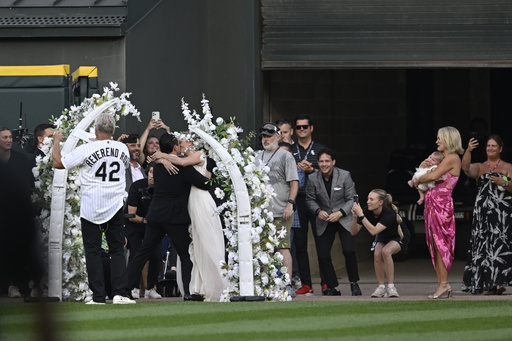 Two lifelong Chicago White Sox fans kiss after exchanging wedding vows during a 60-second wedding officiated by former White Sox player and 1983 rookie of the year Ron Kittle at a baseball game between the White Sox and theCleveland Guardians, Saturday, Aug. 9, 2025, in Chicago. (AP Photo/Paul Beaty)