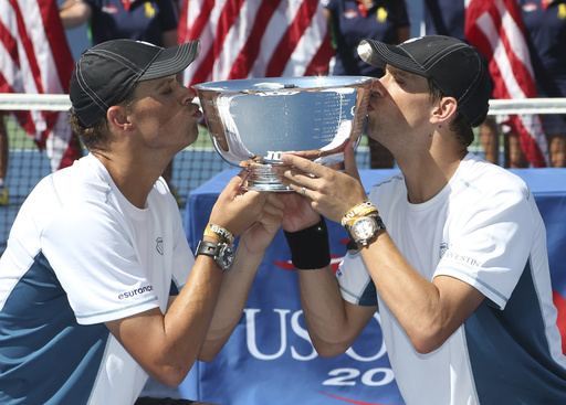 FILE - Bob, left, and Mike Bryan kiss the men's doubles championship trophy after defeating Marc Lopez and Marcel Granollers, of Spain, in the doubles championship match of the 2014 U.S. Open tennis tournament in New York, Sept. 7, 2014. (AP Photo/Mike Groll, File)