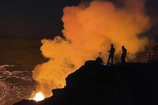 FILE - In this image provided the. the U.S. Geological Survey (USGS), geologist deployed to the rim look over evening views of lava fountaining from Haleumaumau Crater at the summit of Kilauea volcano inside Hawaii Volcanoes National Park, Hawaii., Feb. 11, 2025. ( J. Barnett/U.S. Geological Survey via AP, File)