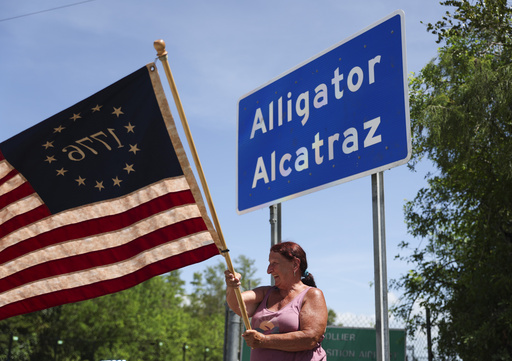 Rana Mourer waves an American flag outside of the migrant detention facility dubbed "Alligator Alcatraz," at the Dade-Collier Training and Transition facility, Saturday, July 12, 2025 in Ochopee, Fla. (AP Photo/Alexandra Rodriguez)