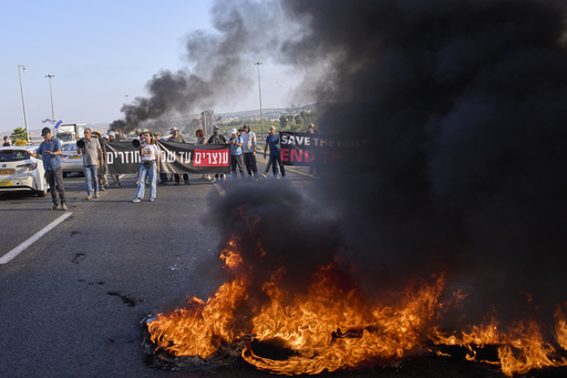 Demonstrators block a road during a protest demanding the immediate release of hostages held by Hamas and calling for the Israeli government to reverse its decision to take over Gaza City and other areas in the Gaza Strip, near Jerusalem, Israel, Sunday, Aug. 17, 2025. (AP Photo/Ohad Zwigenberg)