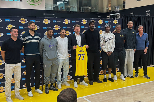 The Los Angeles Lakers, from left, Coach JJ Redick, Maxi Kleber, Marcus Smart, Gabe Vincent, Luka Doncic, Deandre Ayton, Adou Thiero, Rui Hachimura, Jaxson Hayes and general manager Rob Pelinka. congratulate Doncic on his three-year, $165 contract extension at the Lakers' training complex in El Segundo, Calif., on Saturday, Aug. 2, 2025. (AP Photo/Greg Beacham)
