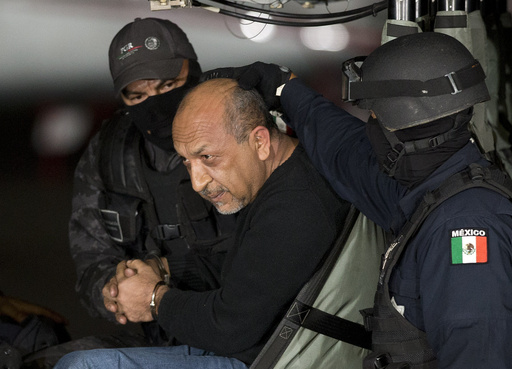 FILE - Mexican federal police escort who they identify as Servando "La Tuta" Gómez," leader of the Knights Templar cartel, as he sits inside helicopter at a Federal hanger in Mexico City, Feb. 27, 2015. (AP Photo/Eduardo Verdugo, File)
