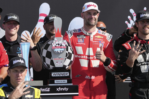 Shane van Gisbergen, center right, poses fort pictures with his team after finishing first during a NASCAR Cup Series auto race in Watkins Glen, N.Y., Sunday, Aug. 10, 2025. (AP Photo/Seth Wenig)