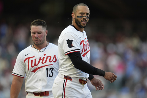 Minnesota Twins' Carlos Correa, right, walks across the field near Ty France (13) after hitting a lineout to third base to end the bottom of the third inning of a baseball game against the Washington Nationals, Saturday, July 26, 2025, in Minneapolis. (AP Photo/Abbie Parr)