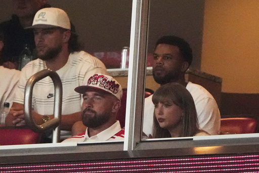 Taylor Swift, front right, sits with fiance Travis Kelce, second from front left, as they watch the first half of an NCAA college football game between Cincinnati and Nebraska, Thursday, Aug. 28, 2025, at Arrowhead Stadium in Kansas City, Mo. (AP Photo/Charlie Riedel)