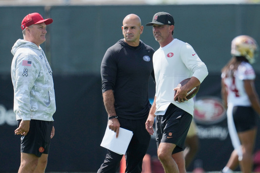 FILE - San Francisco 49ers general manager John Lynch, left, talks with defensive coordinator Robert Saleh, middle, and head coach Kyle Shanahan during practice at the team's NFL football training camp, Wednesday, July 23, 2025, in Santa Clara, Calif. (AP Photo/Jeff Chiu, File)