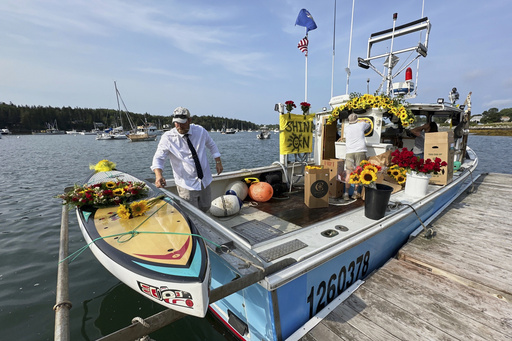 Lobsterman Josh Hupper adds flowers to Sunshine Stewart's paddleboard prior to a memorial service, Sunday, Aug. 10, 2025, in St. George, Maine. (AP Photo/Robert F. Bukaty)