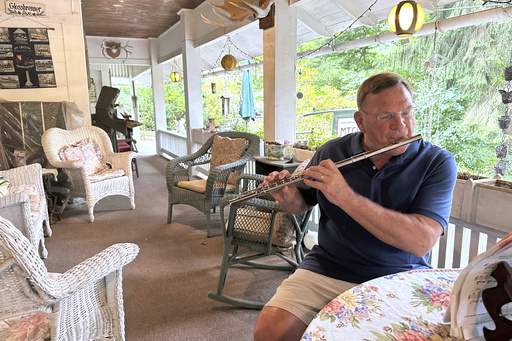 Retired cardiologist Dr. Joe Bering teaches himself flute on the front porch of his cottage in the Campmeeting section of Mount Gretna, Pa., Wednesday, Aug. 6, 2025. (AP Photo/Mark Scolforo)