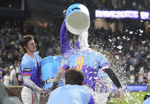 Colorado Rockies' Mickey Moniak, back left, and Orlando Arcia, back right, douse Brenton Doyle (9) after Doyle hit a two-run wakoff home run off Pittsburgh Pirates relief pitcher Dennis Santana in the ninth inning of a baseball game Friday, Aug. 1, 2025, in Denver. (AP Photo/David Zalubowski)