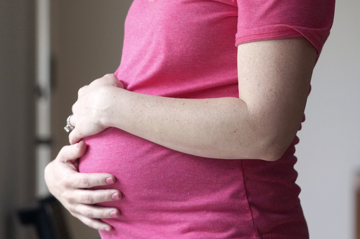 FILE - A pregnant woman stands for a portrait in Dallas, May 18, 2023. (AP Photo/LM Otero, File)