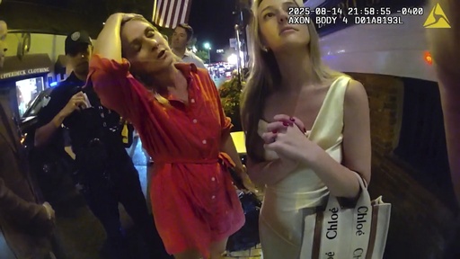 In an image taken from police body camera footage, Newport Police officers interacting with Rhode Island Special Assistant Attorney General Devon Flanagan, in red, and her companions after restaurant representatives indicated that they did not want them on their premises, an encounter that ended with officers detaining Flanagan on trespassing charges, Aug. 14, 2025, in Newport, R.I. (Newport Police Department via AP)