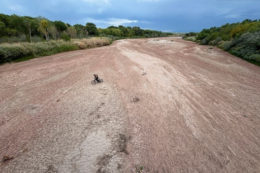 A bicyclist traverses the Rio Grande's dry riverbed in Albuquerque, N.M., on Thursday, Aug. 21, 2025. (AP Photo/Susan Montoya Bryan)