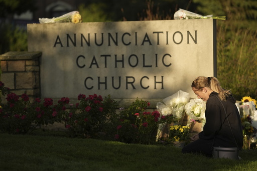 Ann Stovner kneels by a makeshift memorial at Annunciation Catholic Church after Wednesday's school shooting, Thursday, Aug. 28, 2025, in Minneapolis. (AP Photo/Abbie Parr)