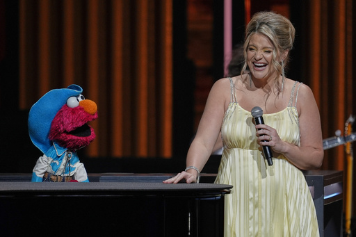 Sesame Street's Elmo, left, performs with Lauren Alaina at the Grand Ole Opry, Thursday, Aug. 14, 2025, in Nashville, Tenn. (AP Photo/George Walker IV)