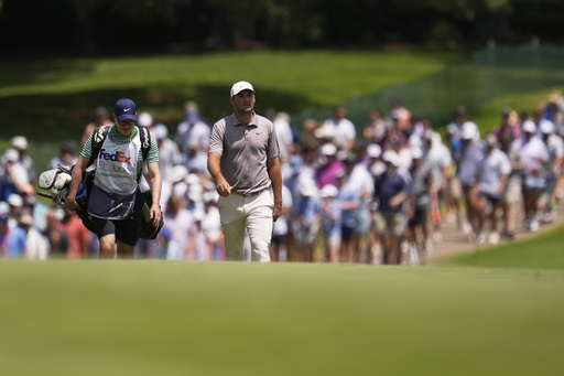 Scottie Scheffler and his caddie walk on the first fairway during the final round of the St. Jude Championship golf tournament Sunday, Aug. 10, 2025, in Memphis, Tenn. (AP Photo/George Walker IV)