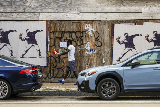 Posters of a person throwing a sandwich are pictured along H Street, Sunday, Aug. 17, 2025, in Washington. (AP Photo/Julia Demaree Nikhinson)