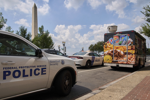 U.S. Department of Homeland Security Federal Protective Services wait on a tow truck to take away a food truck on the National Mall, Friday, Aug. 15, 2025, in Washington. The owner says his employees were asked for immigration status by ICE and then he was told that the truck's tires were bad and it would have to be towed, though he insists it recently passed DC inspection. (AP Photo/Jacquelyn Martin)