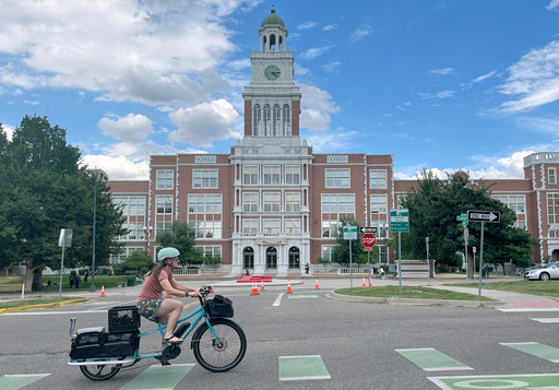 A cyclist rides past East High School in Denver on Thursday, Aug. 28, 2025. (AP Photo/Thomas Peipert)