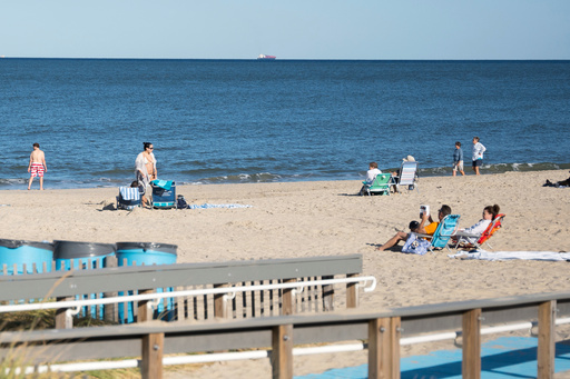People relax at Rehoboth Beach, Del., on Wednesday, Aug. 27, 2025. (AP Photo/Mingson Lau)