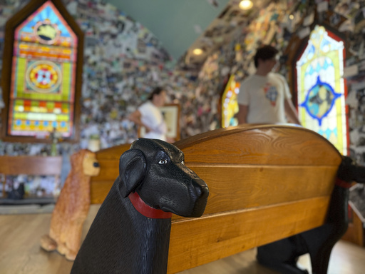 A black lab carved into a wooden pew is pictured in the Dog Chapel at Dog Mountain, a 150-acre dog park created by Vermont folk artist Stephen Huneck, Thursday, Aug. 7, 2025, in St. Johnsbury, Vt. (AP Photo/Amanda Swinhart)