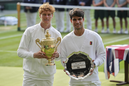 FILE - Italy's Jannik Sinner, left, celebrates with the trophy after beating Carlos Alcaraz of Spain, right, to win the men's singles final at the Wimbledon Tennis Championships in London, July 13, 2025. (AP Photo/Kin Cheung, File)