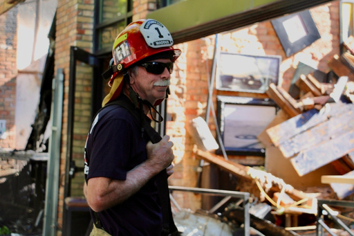 A firefighter surveys the damage of a blaze in downtown Salt Lake City that injured three firefighters and burned several bars and restaurants, Tuesday, Aug. 12, 2025. (AP Photo/Hannah Schoenbaum)