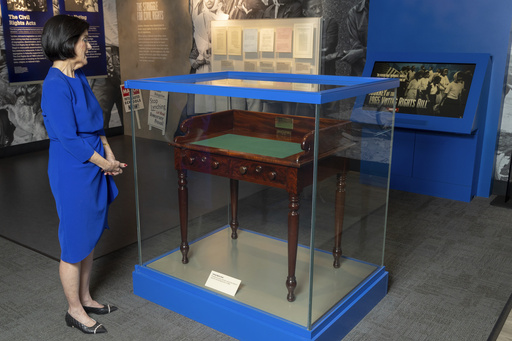 FILE - Luci Baines Johnson looks at the desk May 16, 2023, on display at the LBJ Presidential Library, that President Lyndon B. Johnson sat at in the President's Room at the U.S. Capitol to sign the Voting Rights Act of 1965, on Aug. 6, 1965. (AP Photo/Stephen Spillman, File)