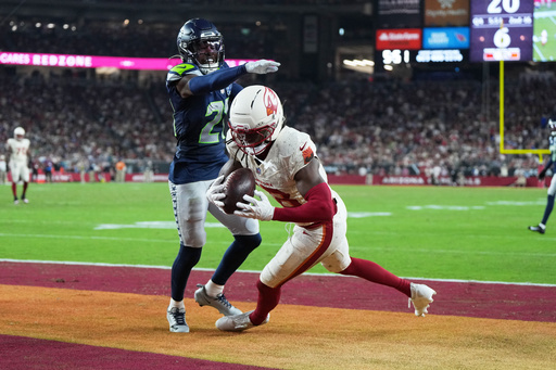 Arizona Cardinals wide receiver Marvin Harrison Jr., right, catches a touchdown pass as Seattle Seahawks cornerback Devon Witherspoon defends during the second half of an NFL football game Thursday, Sept. 25, 2025, in Glendale, Ariz. (AP Photo/Rick Scuteri)