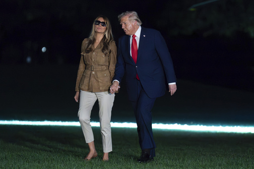 President Donald Trump holds hands with first lady Melania Trump as they walk on the South Lawn upon their arrival to the White House, in Washington, Thursday, Sept. 18, 2025. (AP Photo/Jose Luis Magana)