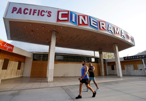 FILE - Pedestrians walk past the boarded up and closed Cinerama Dome movie theater, April 12, 2021, in Los Angeles. (AP Photo/Chris Pizzello, File)