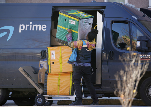 FILE - An Amazon Prime delivery person lifts packages while making a stop at a high-rise apartment building, Nov. 28, 2023, in Denver. (AP Photo/David Zalubowski, File)