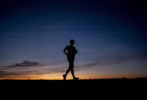 FILE - A man runs on a small road in the outskirts of Frankfurt, Germany, before sunrise on Sept. 8, 2020. (AP Photo/Michael Probst, File)