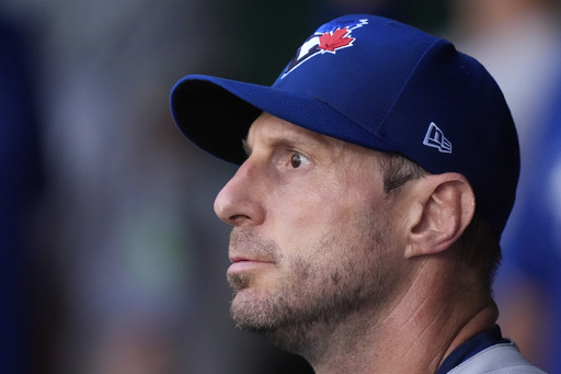 Toronto Blue Jays starting pitcher Max Scherzer watches from the dugout after coming out of the game during the first inning of a baseball game against the Kansas City Royals, Friday, Sept. 19, 2025, in Kansas City, Mo. (AP Photo/Charlie Riedel)
