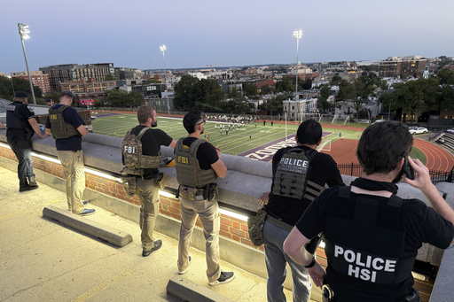 Officers from Metropolitan Police Department, FBI, and Homeland Security Investigations (HSI), are seen monitoring a football game between Bell Multicultural and Archbishop Carroll, Friday, Sept., 12, 2025, at Cardozo High School in the Columbia Heights neighborhood in Washington. (AP Photo/Pablo Martinez Monsivais)