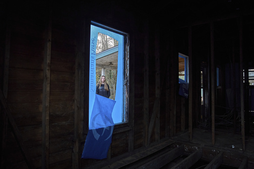 Natalie Briggs looks through a window of her home that was damaged during Hurricane Helene in Swannanoa, N.C., on Tuesday, Dec. 3, 2024. (AP Photo/Stephanie Scarbrough)