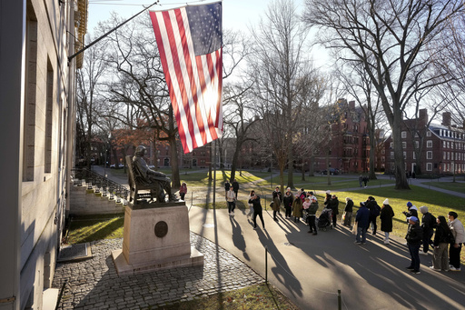 FILE - People take photos near a John Harvard statue, left, on the Harvard University campus, Jan. 2, 2024, in Cambridge, Mass. (AP Photo/Steven Senne, File)