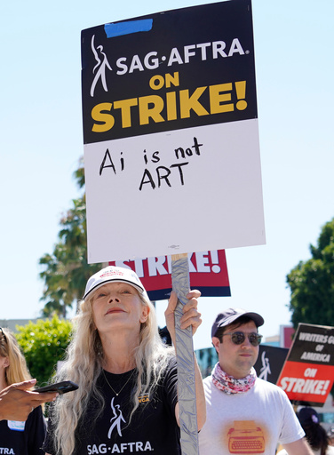 FILE - Actor Frances Fisher holds a sign that says "AI is not art" at a rally by striking writers and actors outside Paramount studios in Los Angeles on July 14, 2023. (AP Photo/Chris Pizzello, File)