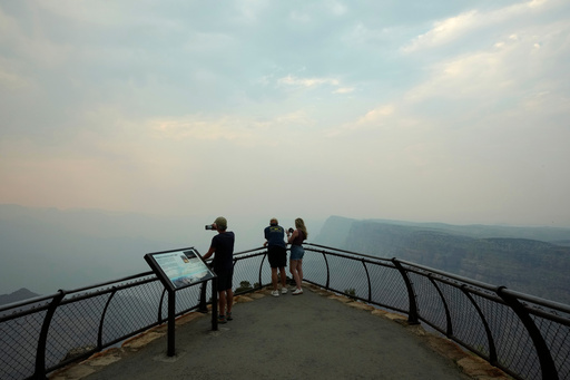 FILE - Smoke from the Dragon Bravo Fire moves over the Grand Canyon from the North Rim blocking the view for tourists at the Desert View overlook July 14, 2025, in Grand Canyon National Park, Ariz. (AP Photo/Ross D. Franklin, File)