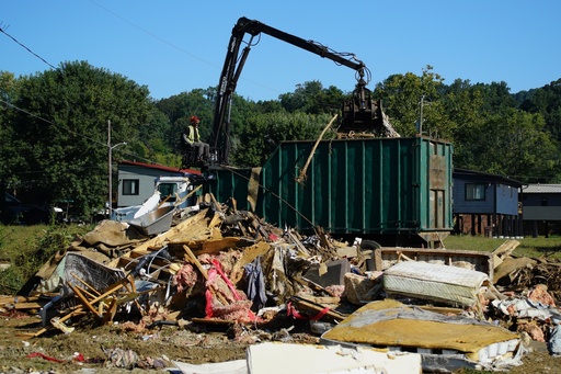 A claw operator scoops up debris from homes demolished following Hurricane Helene in Old Fort, N.C., on Thursday, Sept. 11, 2025. (AP Photo/Allen G. Breed)