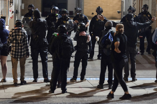 Protesters yell at officers as they walk back to the gates after they created a path for vehicles to exit the U.S. Immigration and Customs Enforcement building in Portland, Ore., on Wednesday, Sept. 10, 2025. (AP Photo/Jenny Kane)